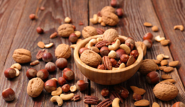 смешанные орехи и сухофрукты на фоне дерева - здоровые закуски