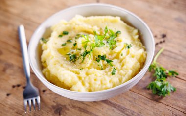 Tahta arka planda tereyağlı ve maydanozlu patates püresi. Rahatlatıcı yemekler ve ev yapımı yemek görselleri için mükemmel.