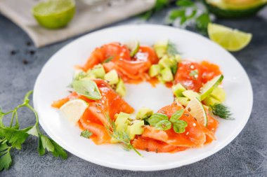 Avokado ve bitkilerle tütsülenmiş somon salatası. Sağlıklı, hafif ve besleyici yemekler için mükemmel.