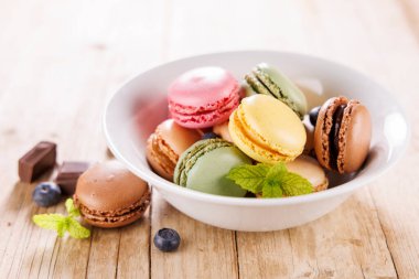 Tahta arka planda bir kase karışık badem kurabiyesi.