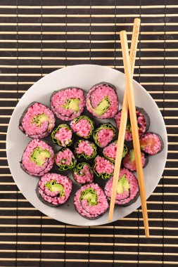 Pembe suşi rulolarının canlı düzenlemesi Taze sebzeler ve pilav ile