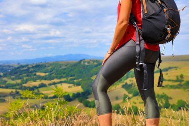 Dişi yürüyüşçü bacakları kayalık dağda duruyor.