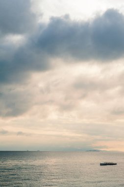 Dramatik gökyüzü, deniz suyu, gemi ve adaları olan güzel bir manzara.