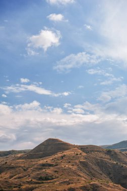 Majestic mountains of Armenia under a blue sky filled with clouds, showcasing natural beauty and rugged terrain