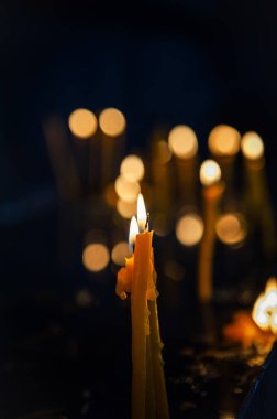 Yumuşak bokeh ışıkları yanan mumu sarıp barışçıl ve ruhani bir atmosfer yaratır.