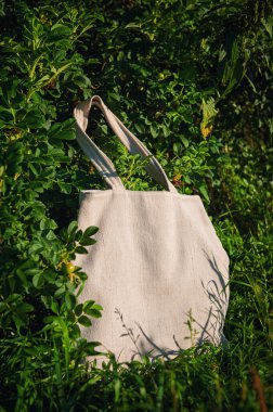 Yeşil bitki yaprakları arasında uzun saplı beyaz tuval şablonu. Tasarımınızı yerleştireceğiniz yüzey