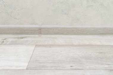 Linoleum wooden floor and plastic skirting board.