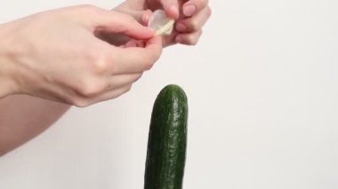 Woman putting condom on a cucumber, tutorial video. Safe sex concept.