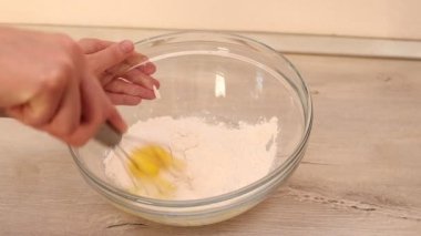 Fırıncı elleri hamuru cam bir kasede çırpıyla yoğurur..