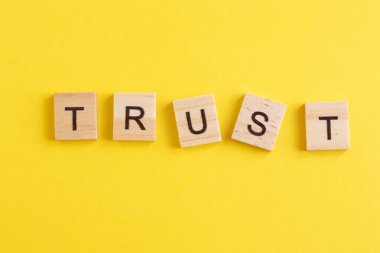 Word TRUST made from wooden letters on yellow background