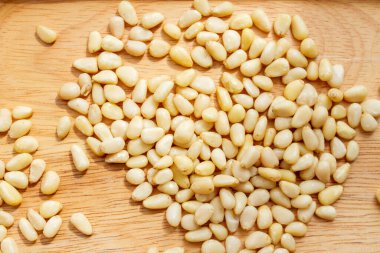 Peeled dried pine nuts on wooden board.