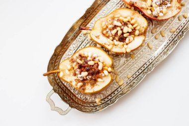 Baked pears with nuts and honey syrupon a silver tray. Classic dessert