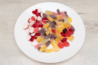 Çeşitli çiğnenebilir şekerler ve tabakta reçel solucanları..