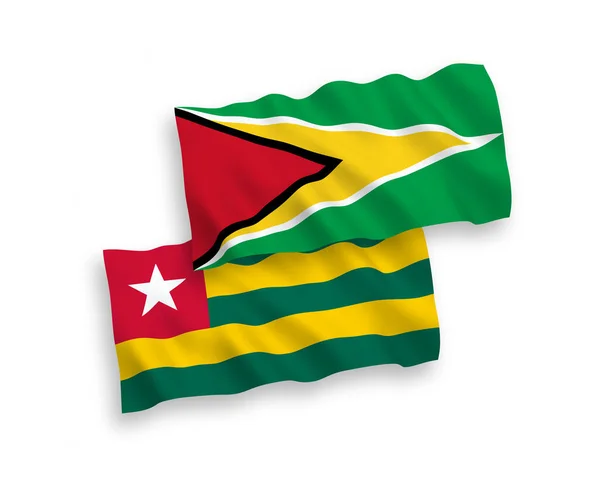 stock vector National vector fabric wave flags of Togolese Republic and Co-operative Republic of Guyana isolated on white background. 1 to 2 proportion.