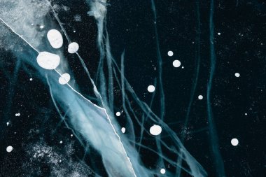 Kışın göl üzerinde çatlaklar ve kabarcıklar olan şeffaf mavi buz. Soyut kış doğa arkaplanı.