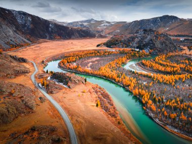 Altai dağlarındaki Chuya nehri ve Chuisky yolu, Sibirya, Rusya. Hava görüntüsü. Gün batımında dağlarda sarı sonbahar ağaçları olan mavi nehir.. 