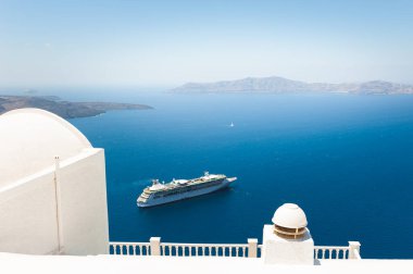 Santorini Adası, Yunanistan 'da beyaz mimari. Yaz deniz manzarası. Kıyıya yakın büyük bir yolcu gemisi. Seyahat ve tatil kavramı