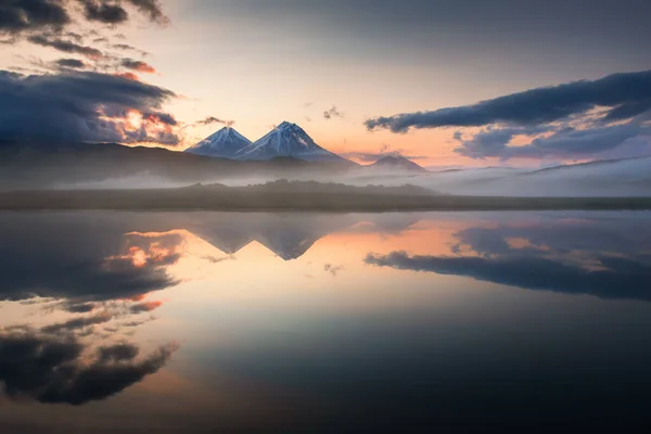 stock image Volcanoes and their reflections in the lake at sunrise in Kamchatka, Russia. Klyuchevskaya Sopka, Kamen and Bezymianny volcanoes in Klyuchevskoy Nature park