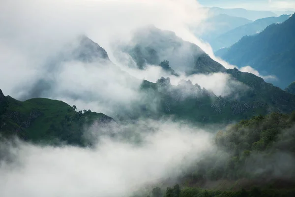 stock image Morning fog in the mountains at sunrise. Clouds over the rocks and trees. Beautiful summer landscape. North Caucasus, Russia.
