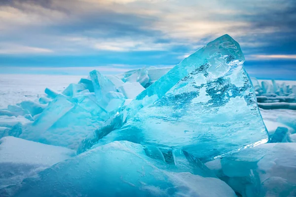 Blue transparent ice on Baikal lake at sunrise. Winter landscape. Baikal, Siberia, Russia. 
