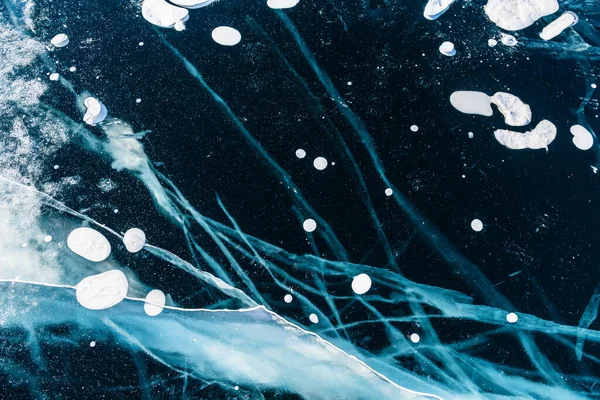 Kışın Baykal Gölü 'nde çatlak ve kabarcıklı şeffaf mavi buz. Soyut kış doğa arkaplanı. 