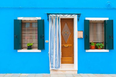 Blue facade of the house with door and windows. Colorful architecture in Burano, Italy.