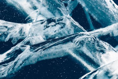 Transparent blue ice with cracks on Baikal lake in winter. Abstract winter nature background.