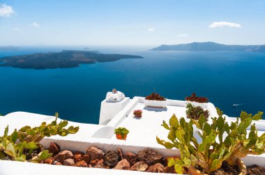 White architecture of Santorini island, Greece. Flowers on the terrace with sea view. Travel and summer vacations concept