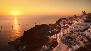 Yunanistan 'ın Santorini adasında güzel bir gün batımı. Oia köyü ve denizinin yatlı panoramik manzarası. Seyahat ve yaz tatili kavramı