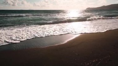 Gün batımında siyah volkanik kum ve mavi deniz olan plaj. Yunanistan 'ın Santorini adasındaki Vlichada plajı. Seyahat ve yaz tatili konsepti