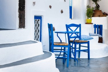 Yunanistan 'ın Santorini adasında geleneksel beyaz ve mavi Yunan mimarisi. Sokakta masalı mavi sandalyeler. 