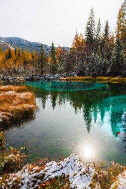 Sonbahar Altai dağlarında mavi gayzer gölü, Sibirya, Rusya. Gün batımında mavi su ve beyaz kar ile göl