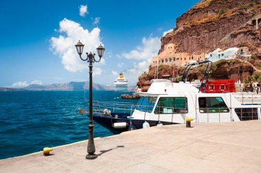 Yunanistan 'ın Santorini adasındaki deniz limanı. Akranlarına yakın bir tekne. Mavi deniz ve mavi gökyüzü. Seyahat ve tatil kavramı