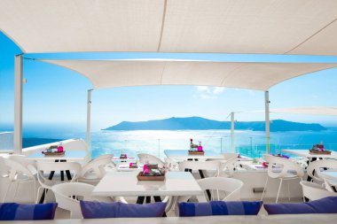 Santorini Adası, Yunanistan. Terasta deniz manzaralı bir kafe. Mavi deniz ve mavi gökyüzü.