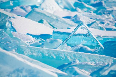 Blue transparent ice with snow on Baikal lake in winter. Selective focus. Winter nature background.