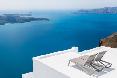 Santorini Adası, Yunanistan 'da beyaz mimari. Terasta deniz manzaralı şezlonglar. Seyahat ve tatil kavramı
