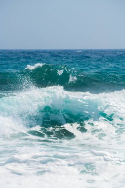 Rüzgarlı bir günde sahilde dalgalar. Santorini Adası, Yunanistan. Mavi deniz ve mavi gökyüzü.
