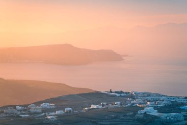 Yunanistan 'ın Santorini adasında pembe sisli gün batımı. Deniz ve adaların manzarası. Güzel yaz deniz manzarası. Meşhur seyahat yeri
