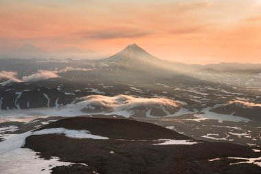 Vilyuchinsky volcano at sunrise in Kamchatka, Russia. Snow-covered mountains with morning fog. Beautiful summer landscape clipart