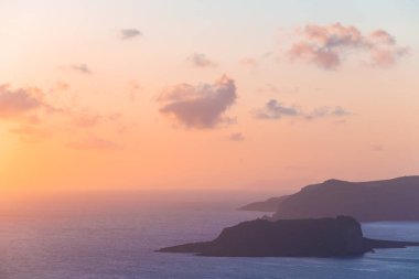 Yunanistan 'ın Santorini adasında pembe sisli gün batımı. Deniz ve adaların manzarası. Güzel yaz deniz manzarası. Meşhur seyahat yeri