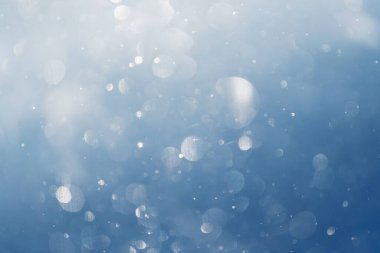 Parlak Bokeh soyut arka planı kış ormanlarında bulanık kar taneleri. Kar taneleri havada döner ve parlar.. 