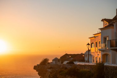 Portekiz, Nazare 'de Atlantik Okyanusu kıyısında güzel bir günbatımı. Uçurumlardaki ulusal mimari. 