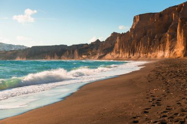 Santorini Adası, Yunanistan. Kırmızı volkanik sünger taşlı Vlichada plajı. Mavi deniz ve siyah volkanik kum. Meşhur seyahat yeri