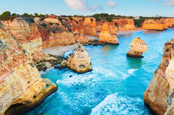 Portekiz, Algarve 'deki Atlantik Okyanusu kıyısındaki kayalar. Sarı kayalar ve mavi su. Gün batımında deniz manzarası. Meşhur seyahat yeri