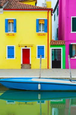 Burano Adası, Venedik, İtalya 'da renkli bir mimari. Kanalda mavi panjurlu ve mavi botlu sarı ev.. 