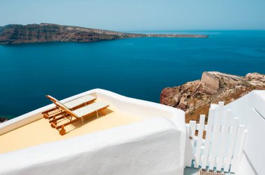 Santorini Adası, Yunanistan. Terasta deniz manzaralı iki şezlong. Seyahat ve yaz tatili konsepti