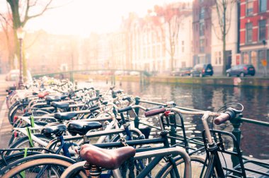 Amsterdam, Hollanda 'da bisiklet parkı. Arka planda geleneksel Hollandalı mimarisi olan manzara kanalı.
