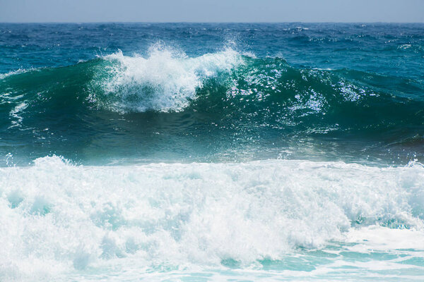 Waves on the beach in windy day. Blue sea and the blue sky. Mediterranean sea, Santorini island, Greece.