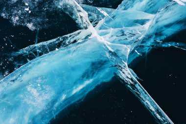 Transparent blue ice with cracks on Baikal lake in winter. Abstract winter nature background.