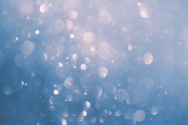 Kış ormanında bulanık kar taneleri. Parlak Bokeh soyut arkaplanı. Kar taneleri havada döner ve parlar..